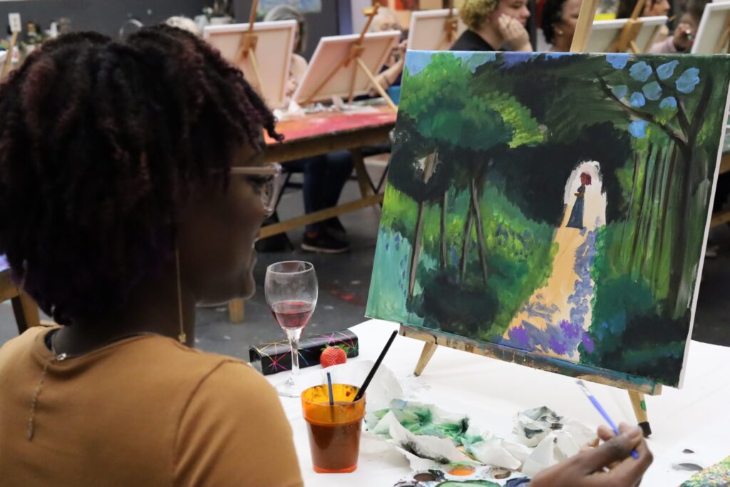 woman smiles while painting a landscape of a garden