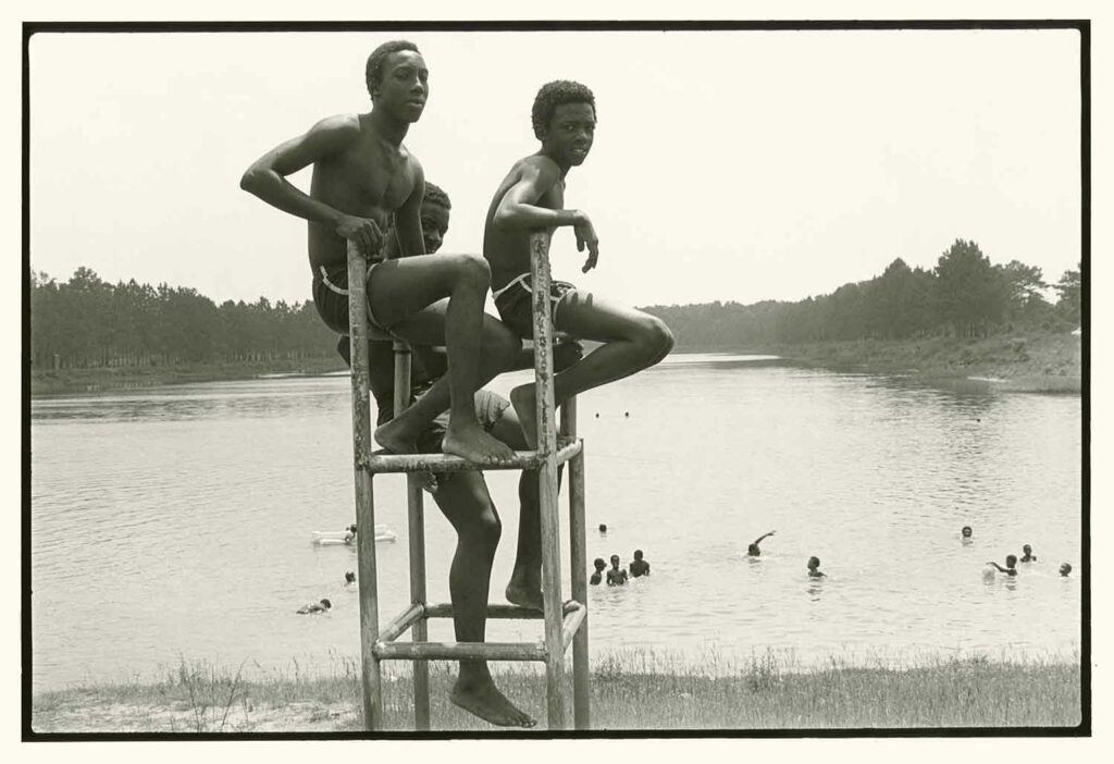 Young African-American males sit in lifeguard chair with Flint River basin in background