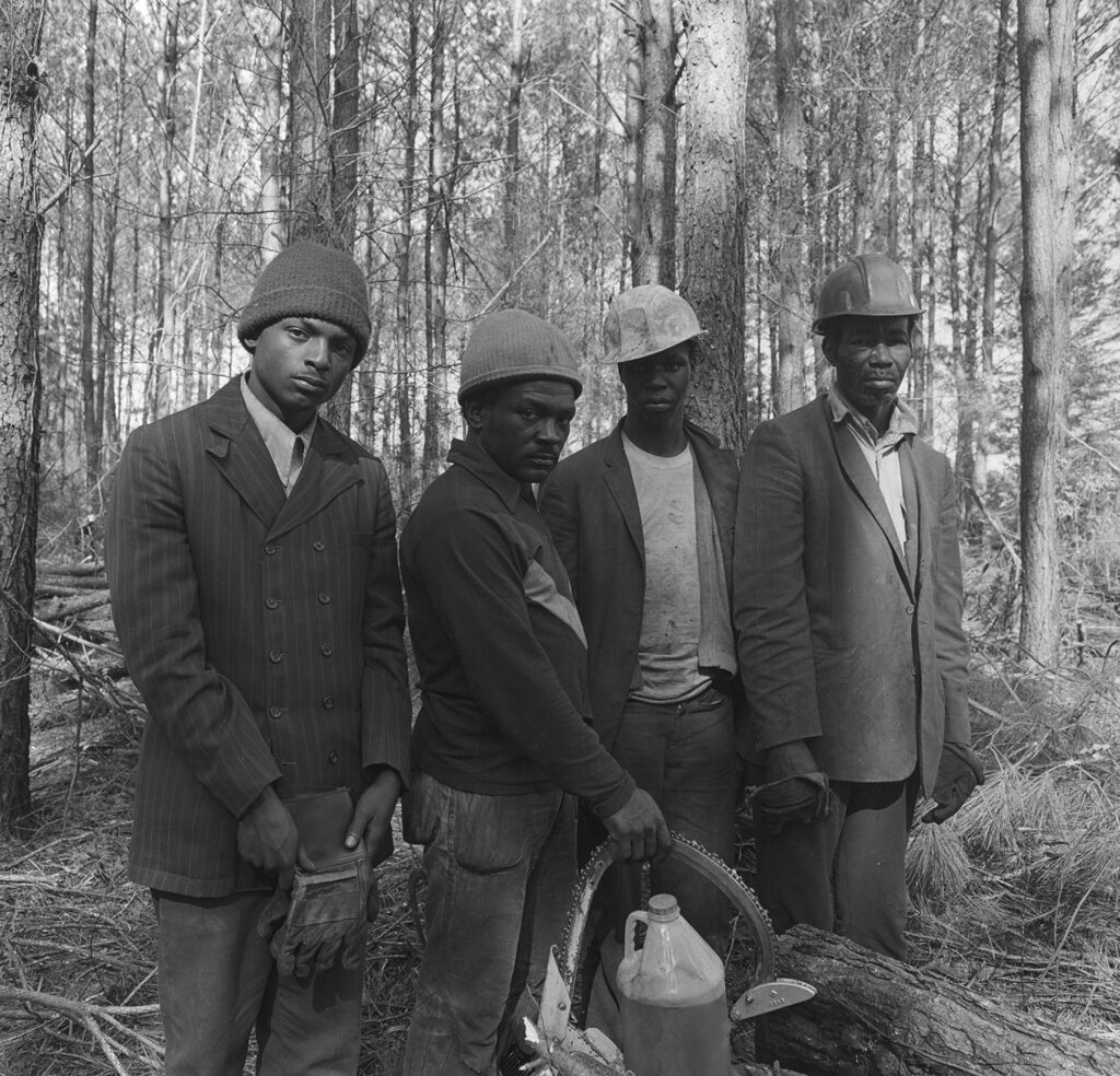 Four African American loggers stand in woods