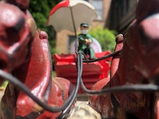 Figure of man with umbrella holds reins on figure of horse