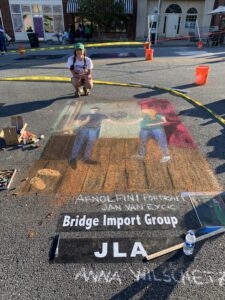 Artist poses with chalk art image of man and pregnant woman