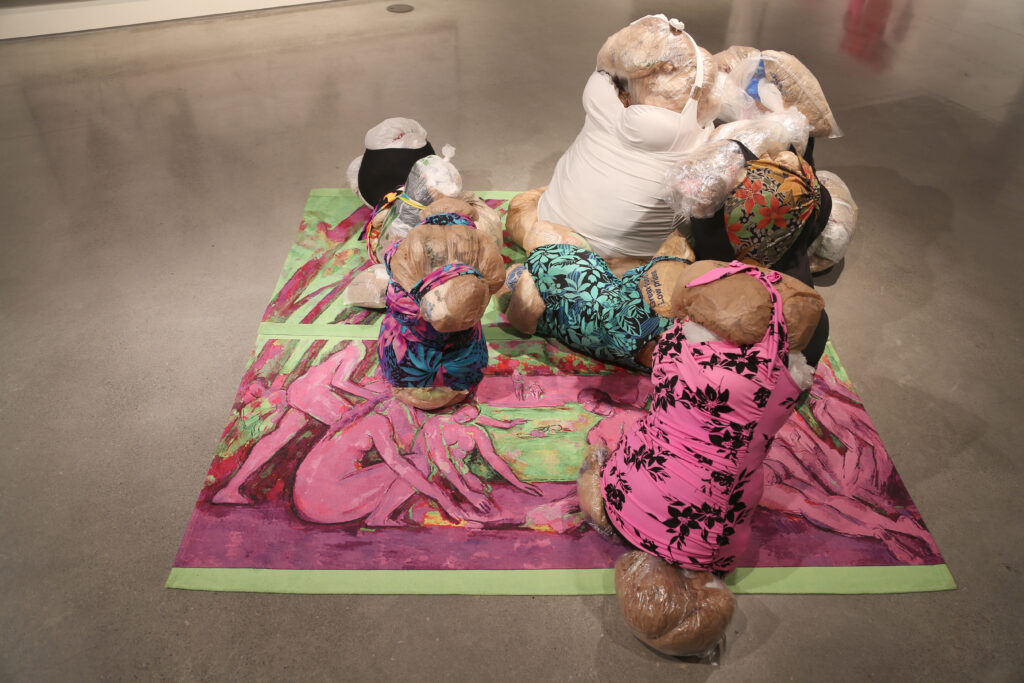 soft sculpture of swimsuits and grocery bags depicting a beach party scene