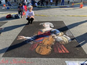 Artist poses with chalk image of woman with violin