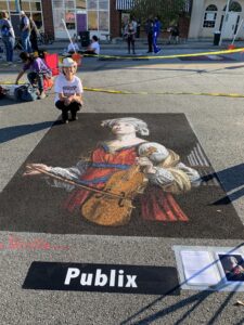 Artist poses with chalk image of woman with violin