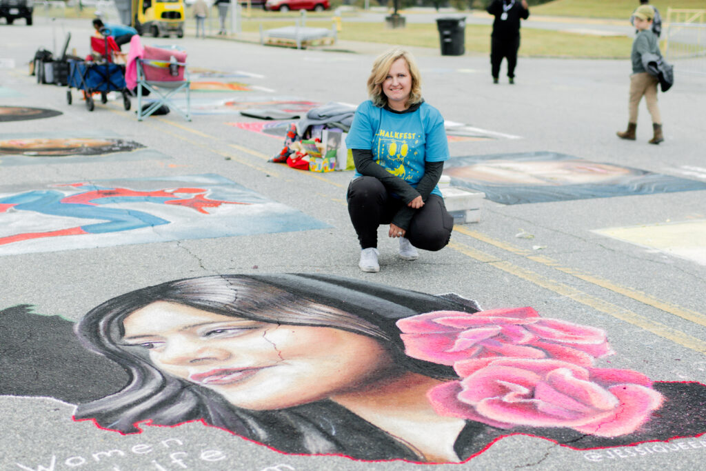 chalk artists Jessi Queen poses with her winning entry in ChalkFest 2022