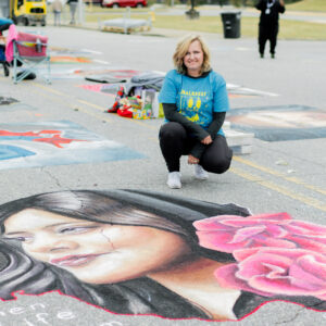 chalk artists Jessi Queen poses with her winning entry in ChalkFest 2022