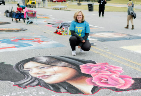 chalk artists Jessi Queen poses with her winning entry in ChalkFest 2022