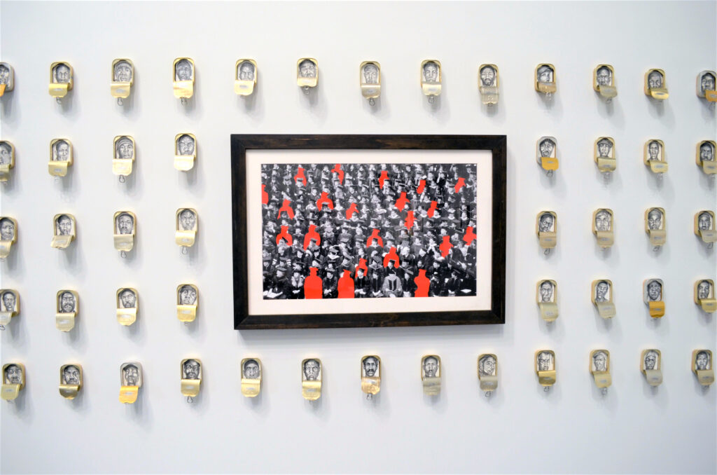 Images of imprisoned black men are placed inside sardine cans and images of black graduates are covered in red to show the loss of individuals to a penal system