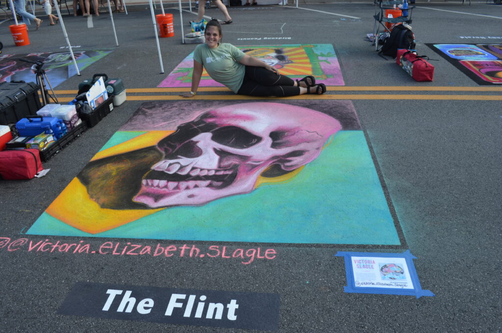 Artist poses with pop art chalk image of a skull