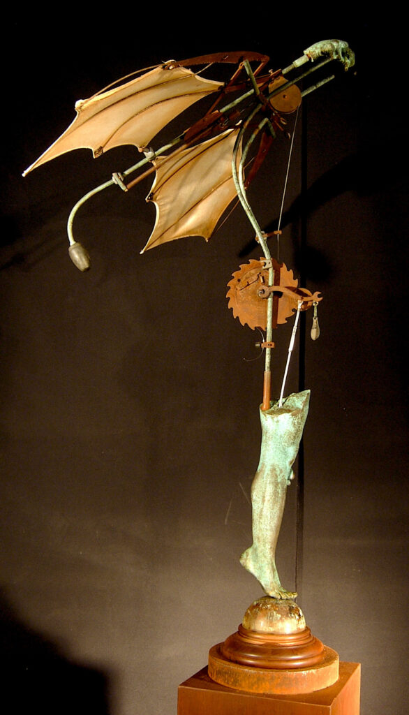 Wood and bronze sculpture mimmicks a flying bird and is animated so that its wings open and close