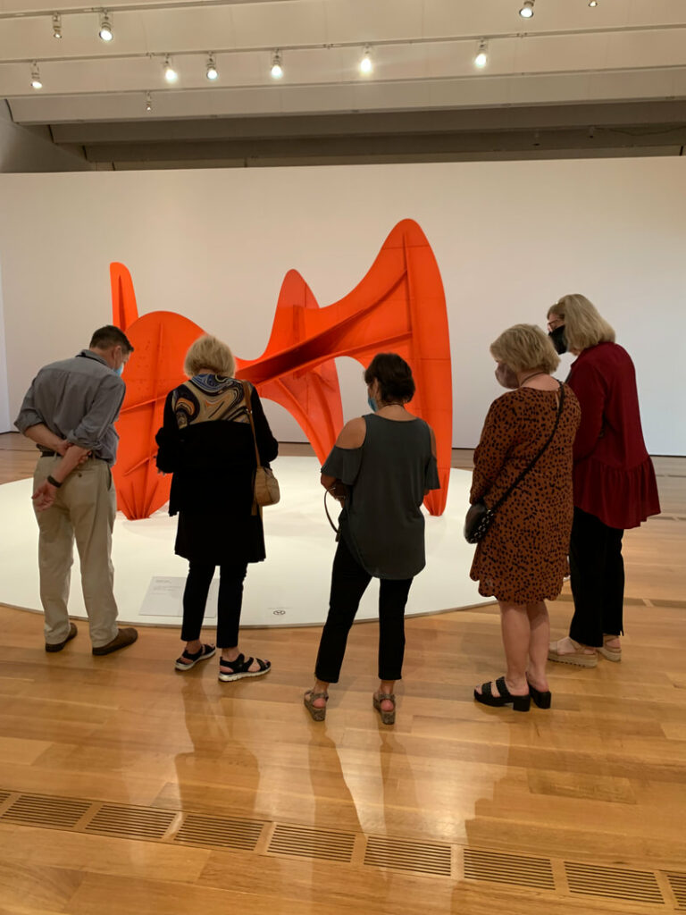 Five people look at large sculpture in museum