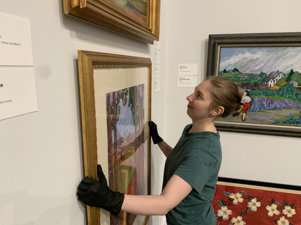 Curator Katie Dillard hangs an artwork in the Haley Gallery of the Albany Museum of Art