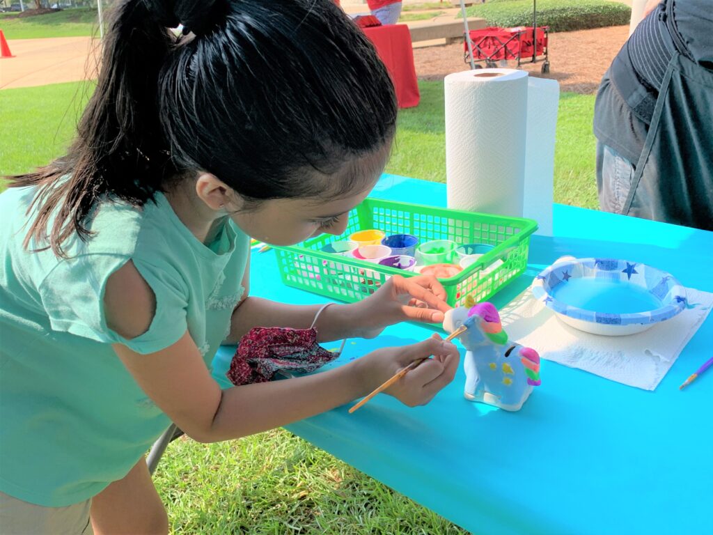Girl completes art project under tent at Albany Museum of Art outdoor Family Day