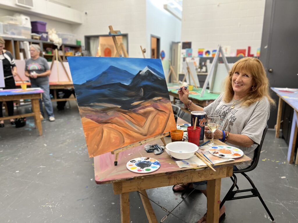 woman smiles as she is painting