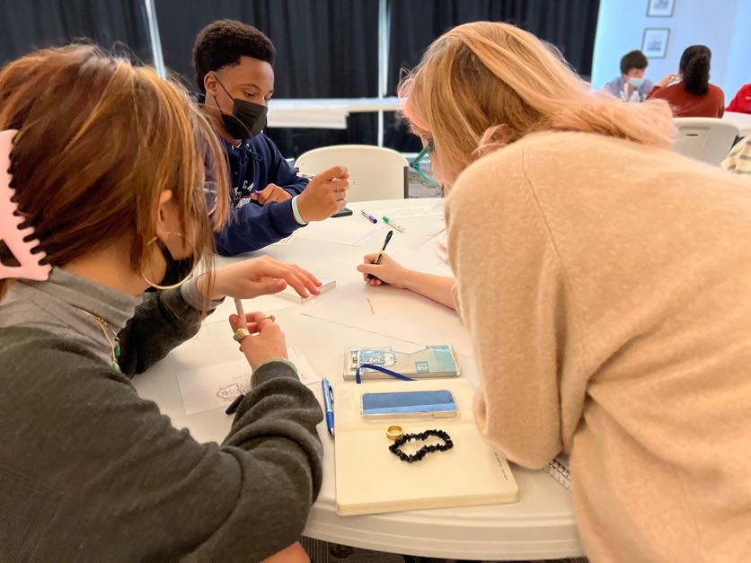 Three students work on a project at an AMA workshop