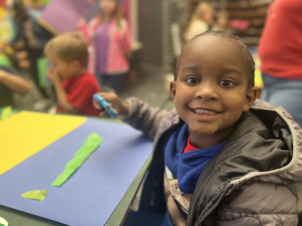 Young boy smiles while working on an art project