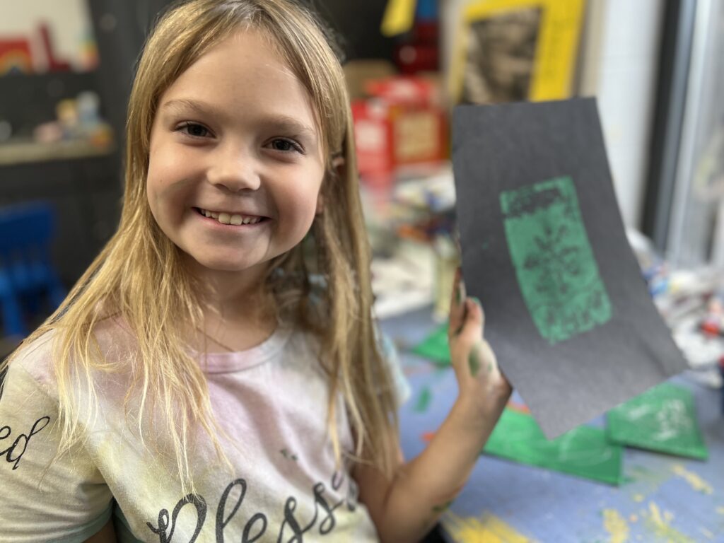Girl smiles while showing art project
