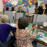 Participants in a painting class work on canvases