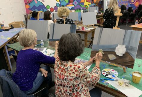 Participants in a painting class work on canvases