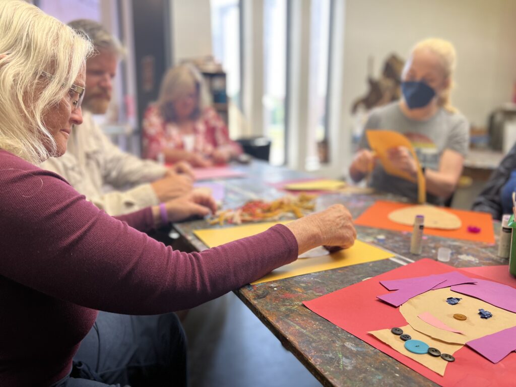 Adults do an art project in the AMA classroom
