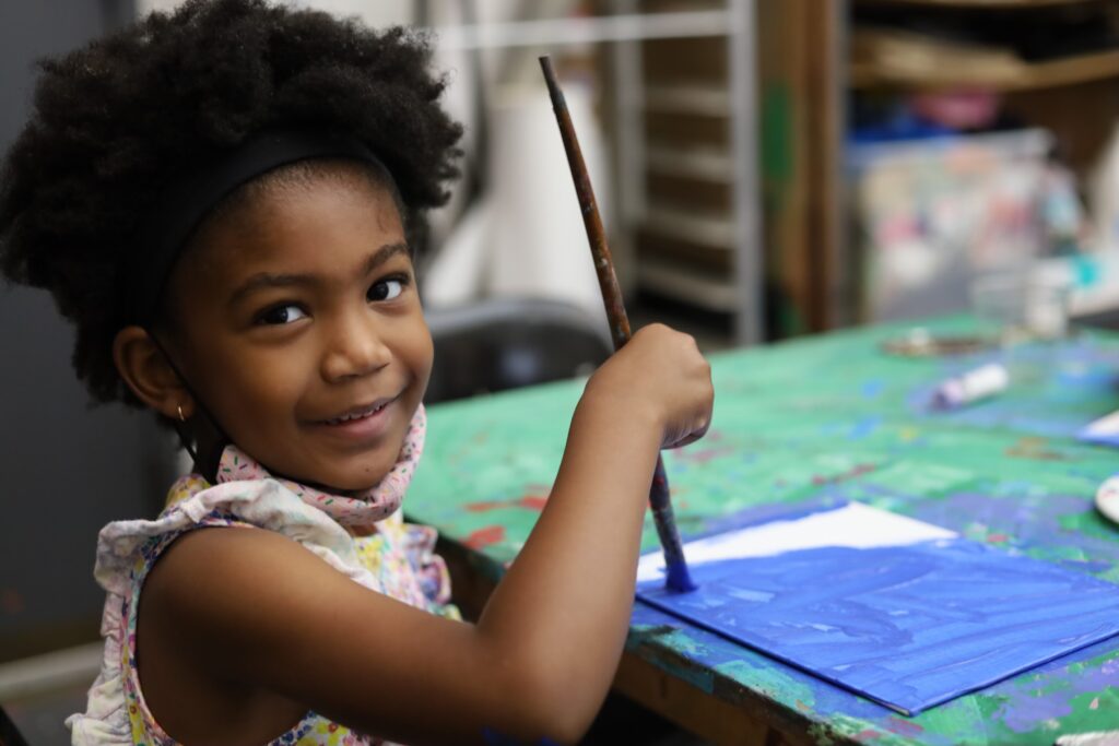 Young girls smiles while painting with brush