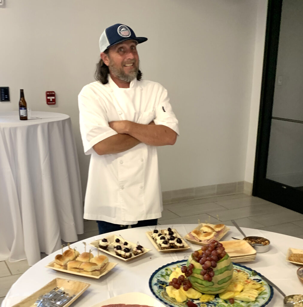 Chef Todd White stands at food table at April 2023 opening reception at the Albany Museum of Art