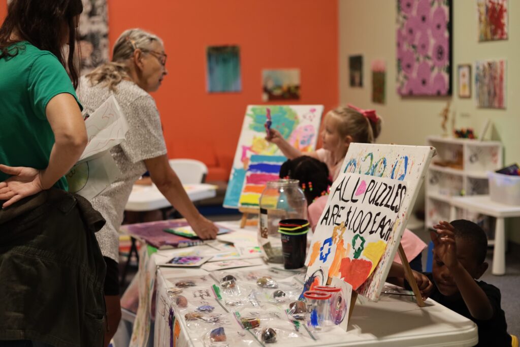 Adults look at art products created by campers at Artrepreneur Camp