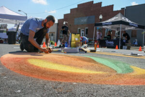 Artist works on large chalk image of peach on downtown Albany street
