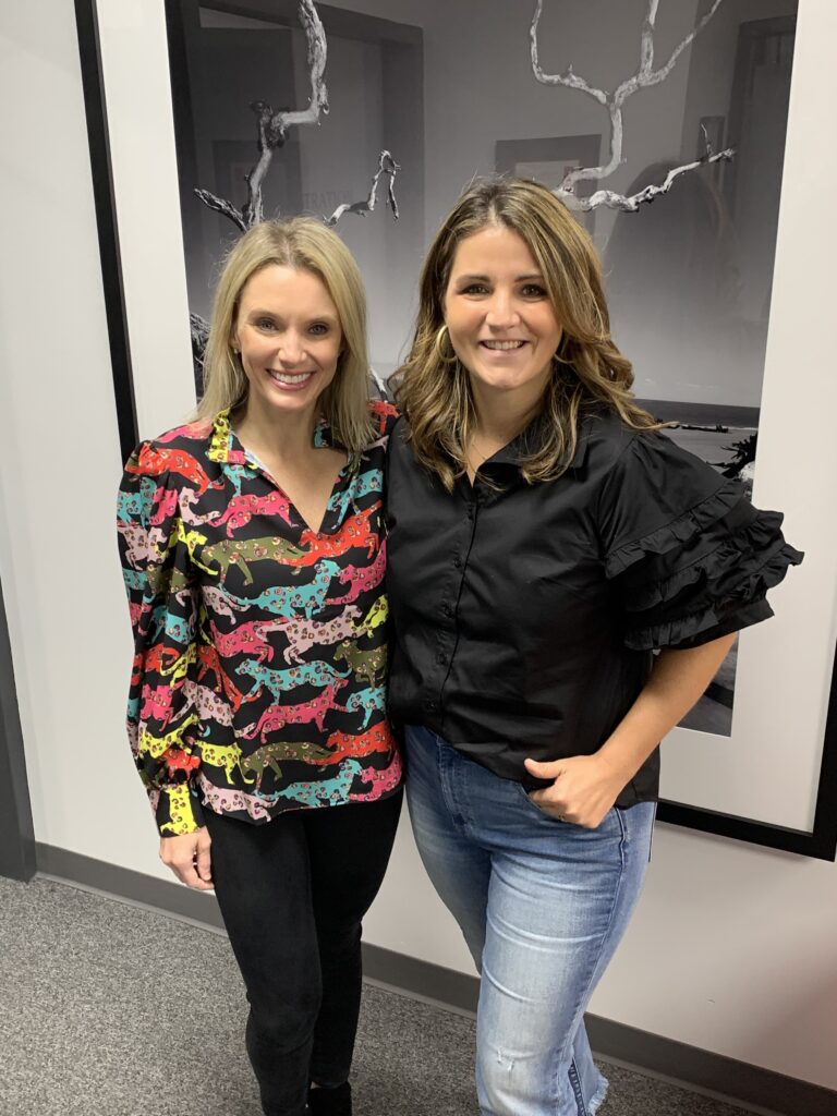 two women stand in front of a large black and white photograph