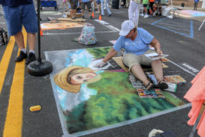 Artist creates chalk image of woman in rural setting
