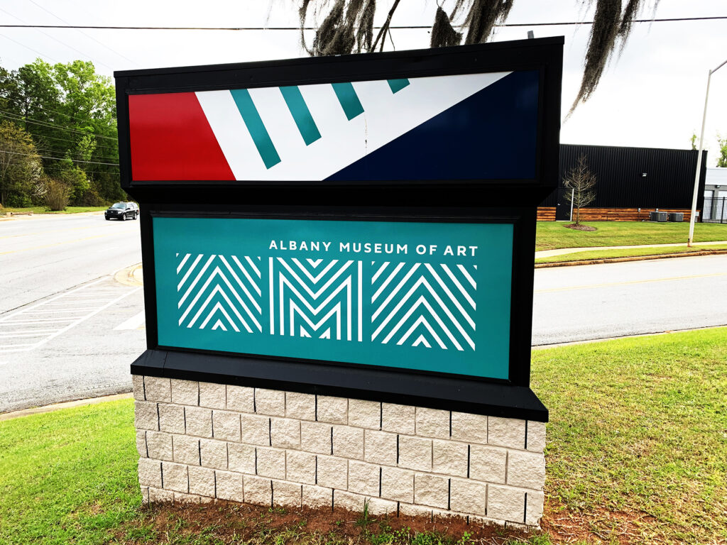 Albany Museum of Art logo in white on a teal background in one face of a three-sided roadside sign