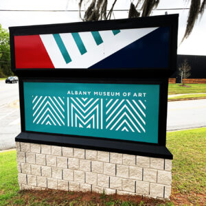 Albany Museum of Art logo in white on a teal background in one face of a three-sided roadside sign