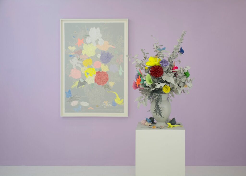 A flower arrangement is on a pedestal in front of a painting of the same arrangement
