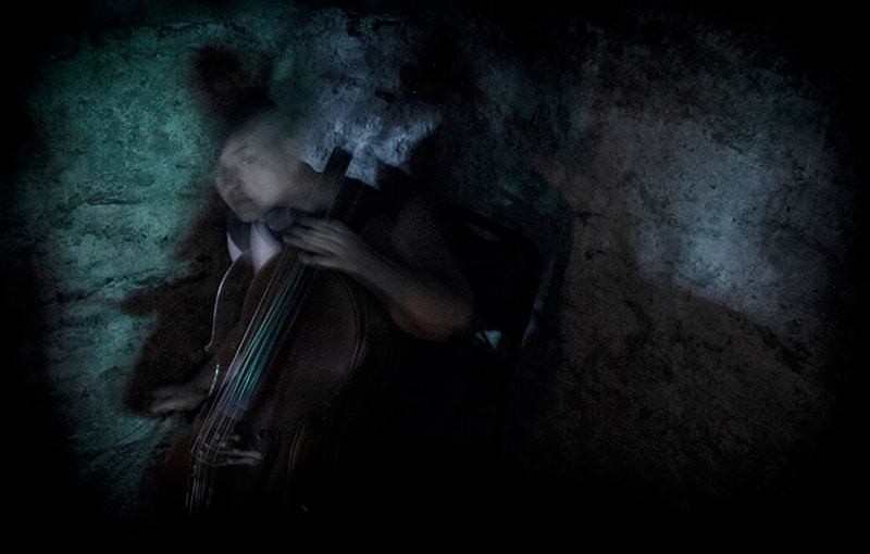 Woman plays cello with out-of-focus surroundings